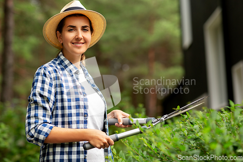 Image of woman with pruner cutting branches at garden