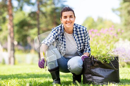 Image of woman weeding flowerbed at summer garden