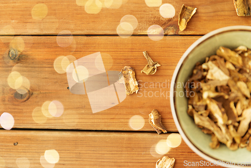 Image of dried mushrooms in bowl on wooden background