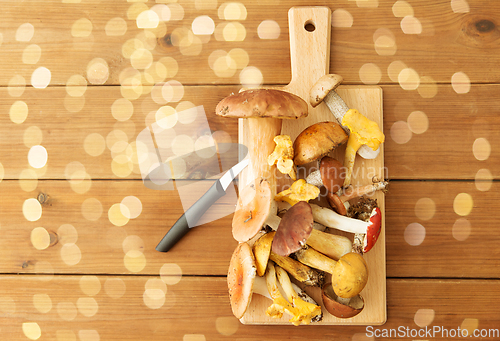 Image of edible mushrooms on wooden cutting board and knife