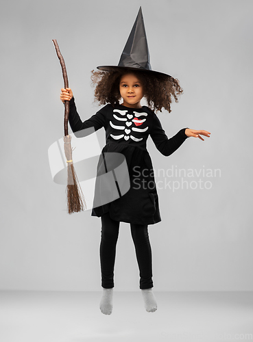 Image of girl in black witch hat with broom on halloween