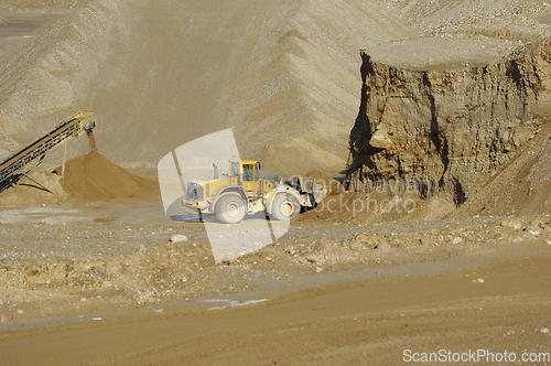 Image of A yellow wheel loader is working in gravel pit