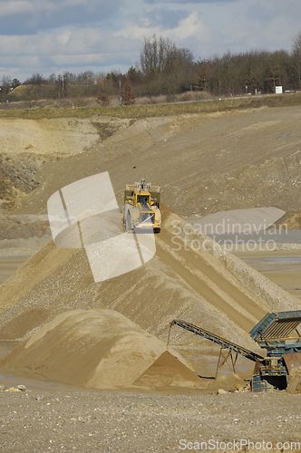 Image of A yellow wheel loader is working in gravel pit