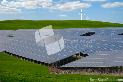 Image of Rows of solar panels, wind turbine and green nature