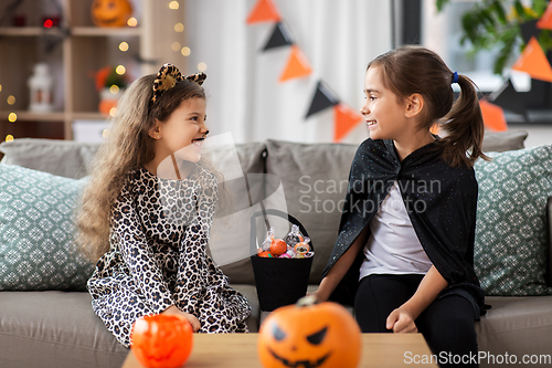 Image of girls in halloween costumes with candies at home