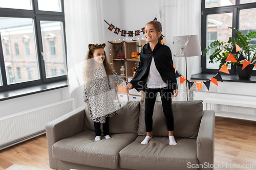 Image of girls in halloween costumes jumping on sofa