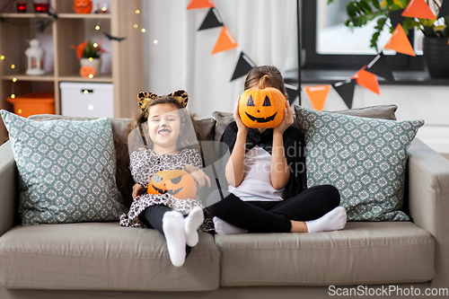 Image of girls in halloween costumes with pumpkins at home