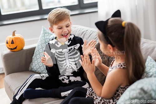 Image of kids in halloween costumes playing game at home