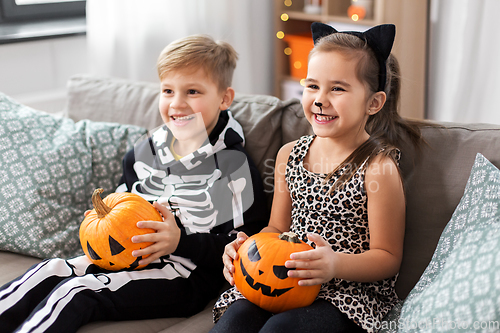 Image of kids in halloween costumes with pumpkins at home