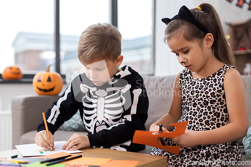 Image of kids in halloween costumes doing crafts at home