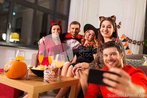 Image of happy friends in halloween costumes taking selfie