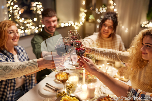 Image of happy friends drinking red wine at christmas party