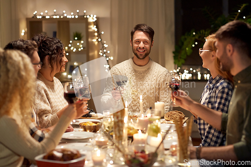 Image of happy friends drinking red wine at christmas party