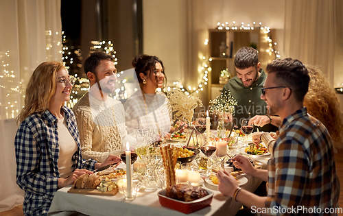 Image of happy friends having christmas dinner at home