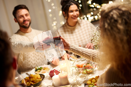 Image of happy friends drinking red wine at christmas party