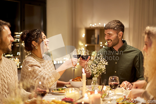 Image of happy friends drinking red wine at christmas party