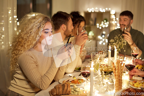 Image of woman with smartphone at dinner party with friends