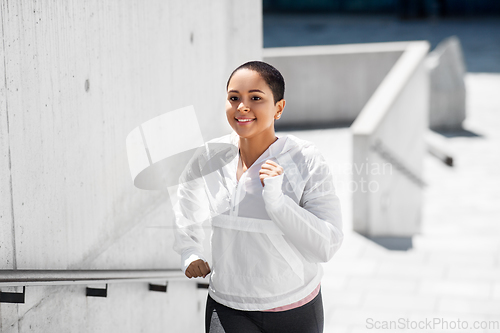 Image of african american woman running upstairs outdoors