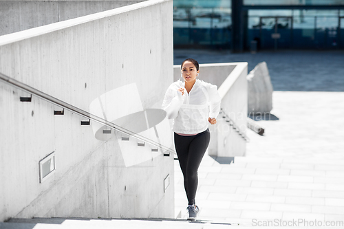 Image of african american woman running upstairs outdoors