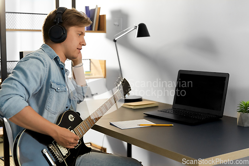 Image of man in headphones playing bass guitar at home