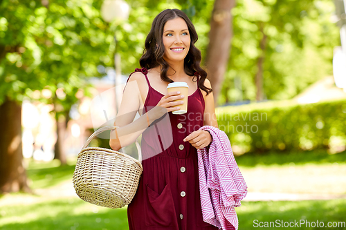 Image of happy woman with picnic basket and coffee at park