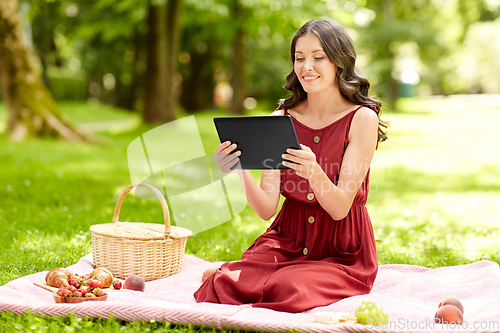 Image of happy woman with tablet computer on picnic at park