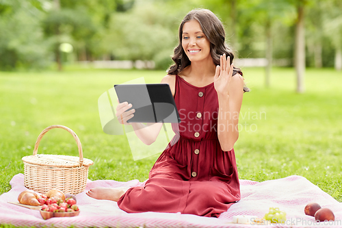 Image of woman with tablet pc having video call at picnic