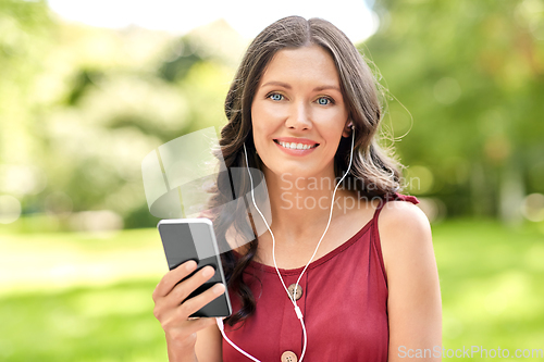 Image of woman with smartphone and earphones at park