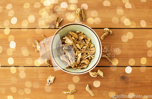 Image of dried mushrooms in bowl on wooden background