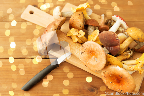 Image of edible mushrooms on wooden cutting board and knife