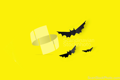 Image of flock of black paper bats over yellow background