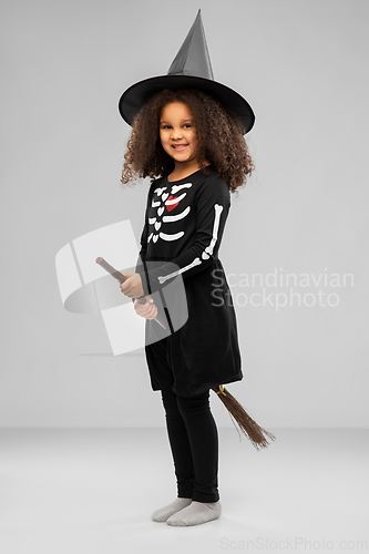 Image of girl in black witch hat with broom on halloween