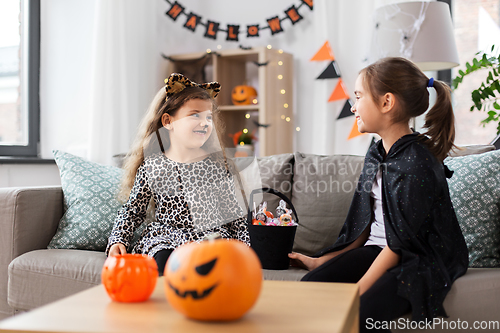 Image of girls in halloween costumes with candies at home