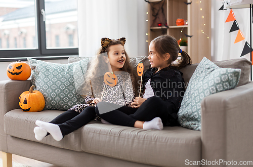 Image of girls in halloween costumes with pumpkins at home