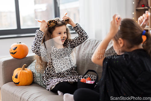 Image of girls in halloween costumes with candies at home