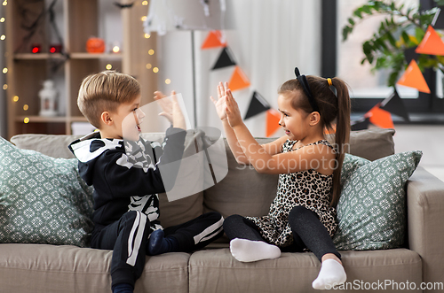 Image of kids in halloween costumes playing game at home