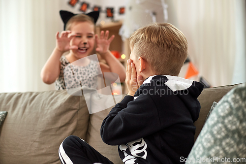 Image of kids in halloween costumes having fun at home