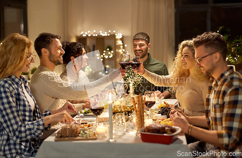 Image of happy friends drinking red wine at christmas party