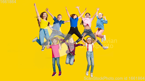 Image of Portrait of little children jumping isolated on yellow studio background with copyspace