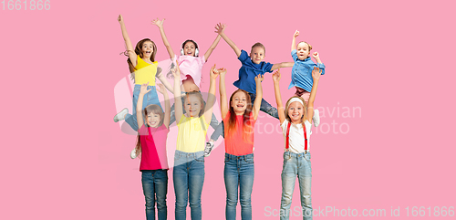 Image of Portrait of little children jumping isolated on pink studio background with copyspace