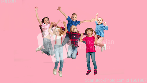 Image of Portrait of little children jumping isolated on pink studio background with copyspace
