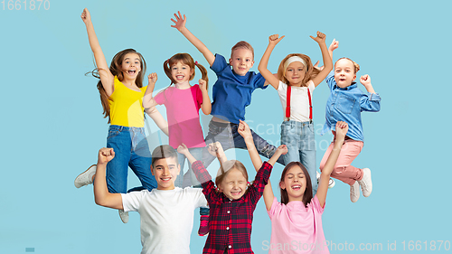 Image of Portrait of little children jumping isolated on blue studio background with copyspace
