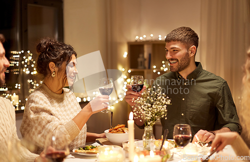 Image of happy friends drinking red wine at christmas party