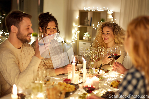 Image of happy friends drinking red wine at christmas party