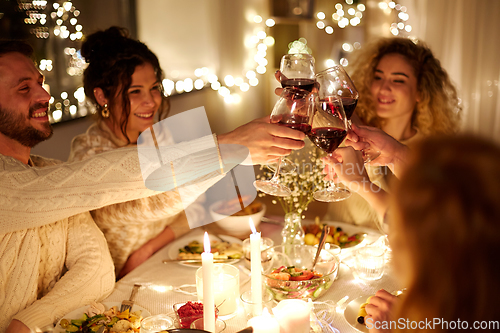 Image of happy friends drinking red wine at christmas party