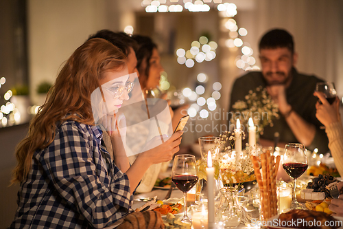 Image of woman with smartphone at dinner party with friends