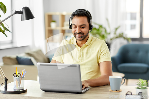 Image of indian man with headset and laptop working at home