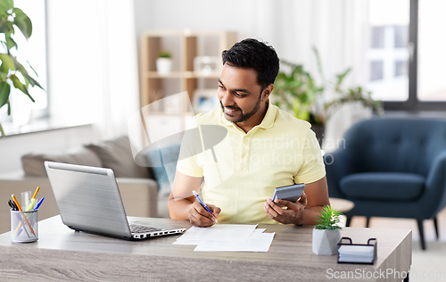 Image of man with calculator and papers working at home