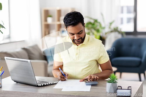 Image of man with calculator and papers working at home