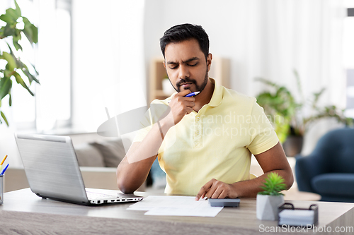 Image of man with calculator and papers working at home